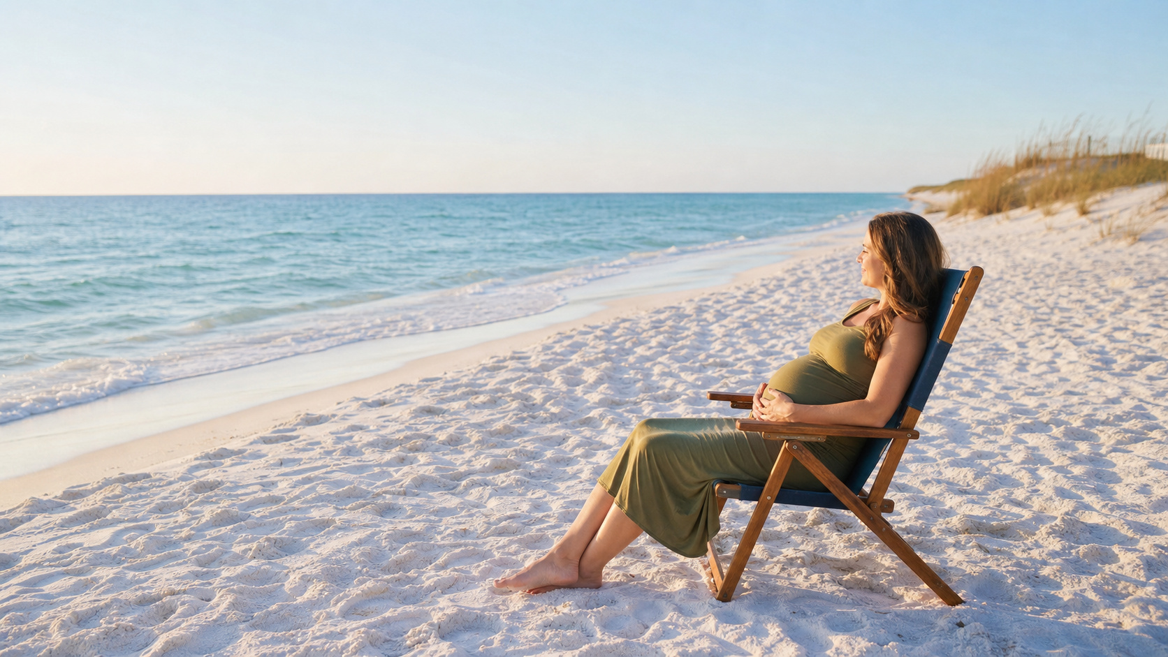 Pregnant woman relaxing in a beach chair on a quiet stretch of white sand in Destin Florida, turquoise Gulf water, early morning calm light