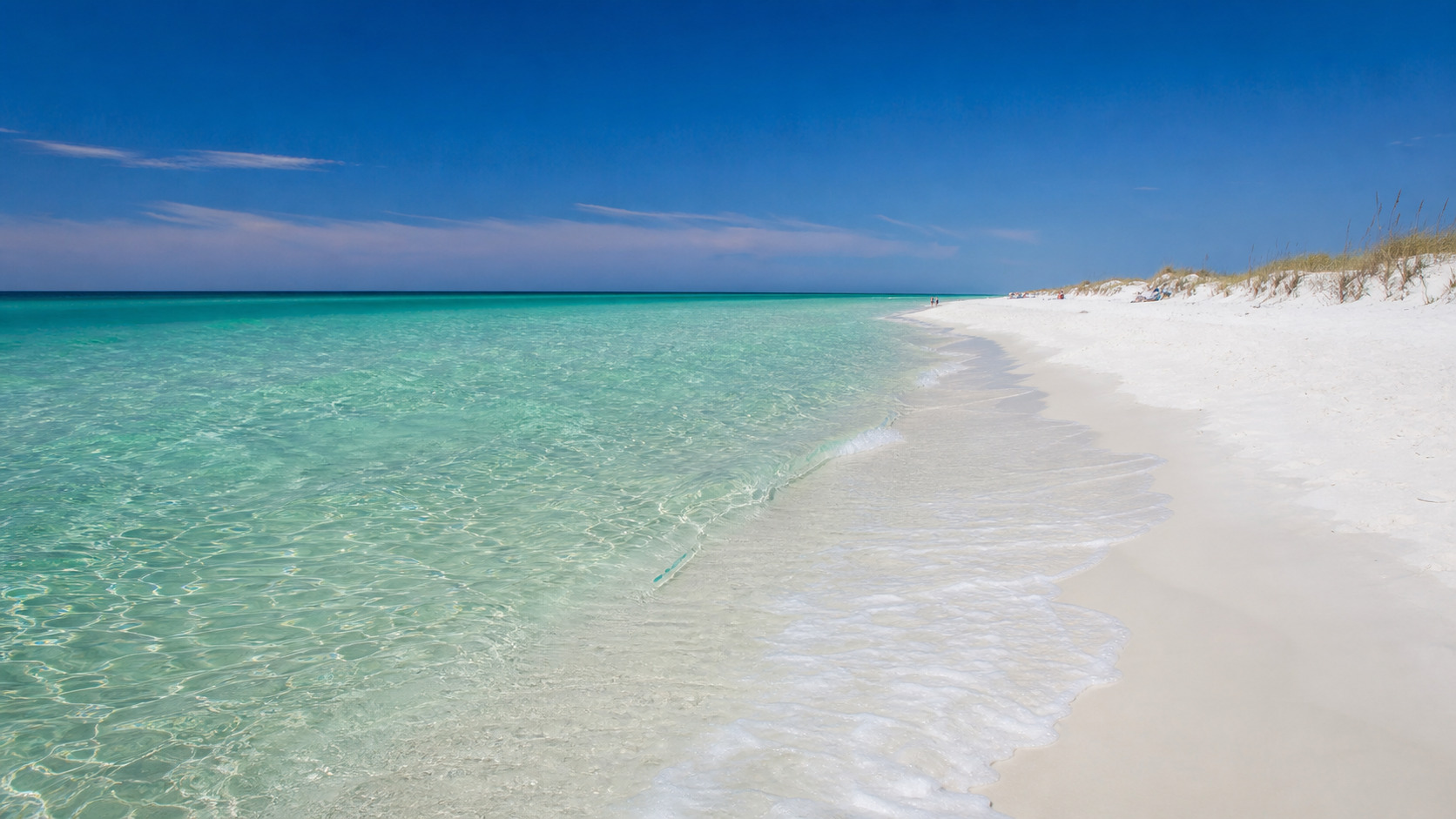 Crystal-clear emerald green Gulf water lapping the brilliant white quartz sand beach at Destin Florida on a sunny summer day