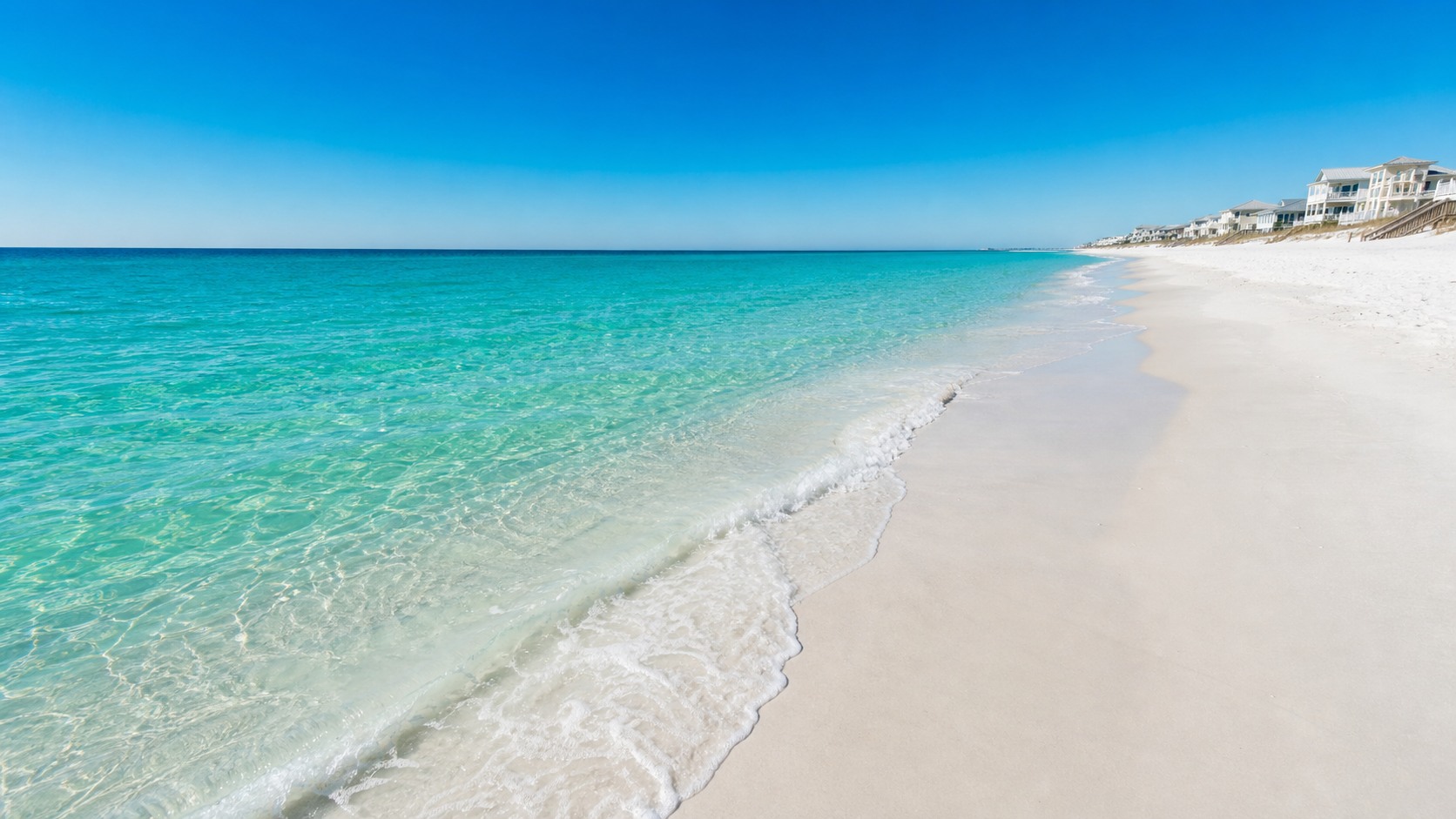 Wide-angle shot of Destin Florida beach with brilliant emerald-green Gulf water, white quartz sand, and calm gentle waves on a clear summer morning