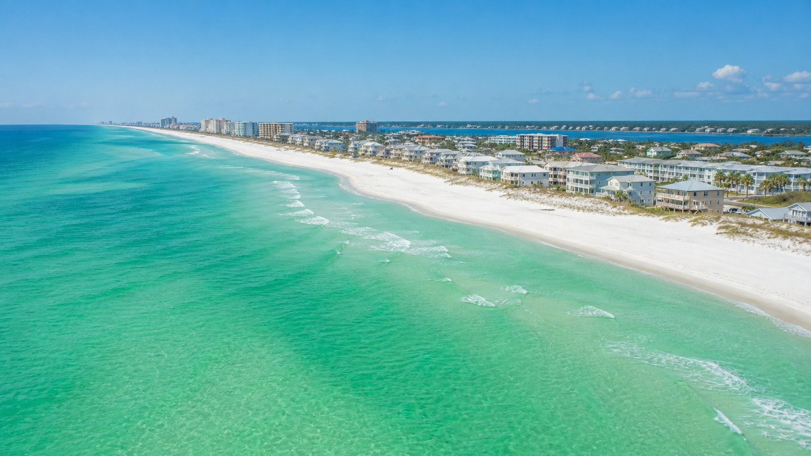 Aerial view of Destin Florida's emerald green Gulf water and sugar-white sand beach on a clear summer day