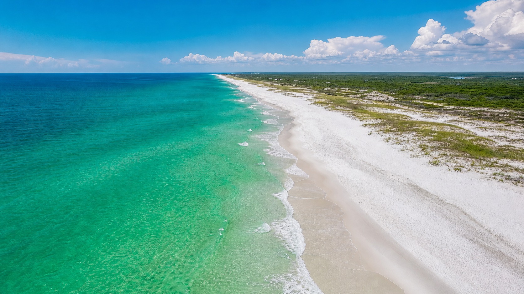Aerial view of Destin Florida beach from above with emerald-green Gulf water, brilliant white sand and a long stretch of coastline on a clear summer day