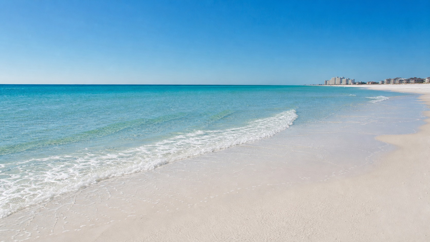 Destin Florida powdery white quartz sand and brilliant emerald-green Gulf water on a clear summer morning with small gentle waves