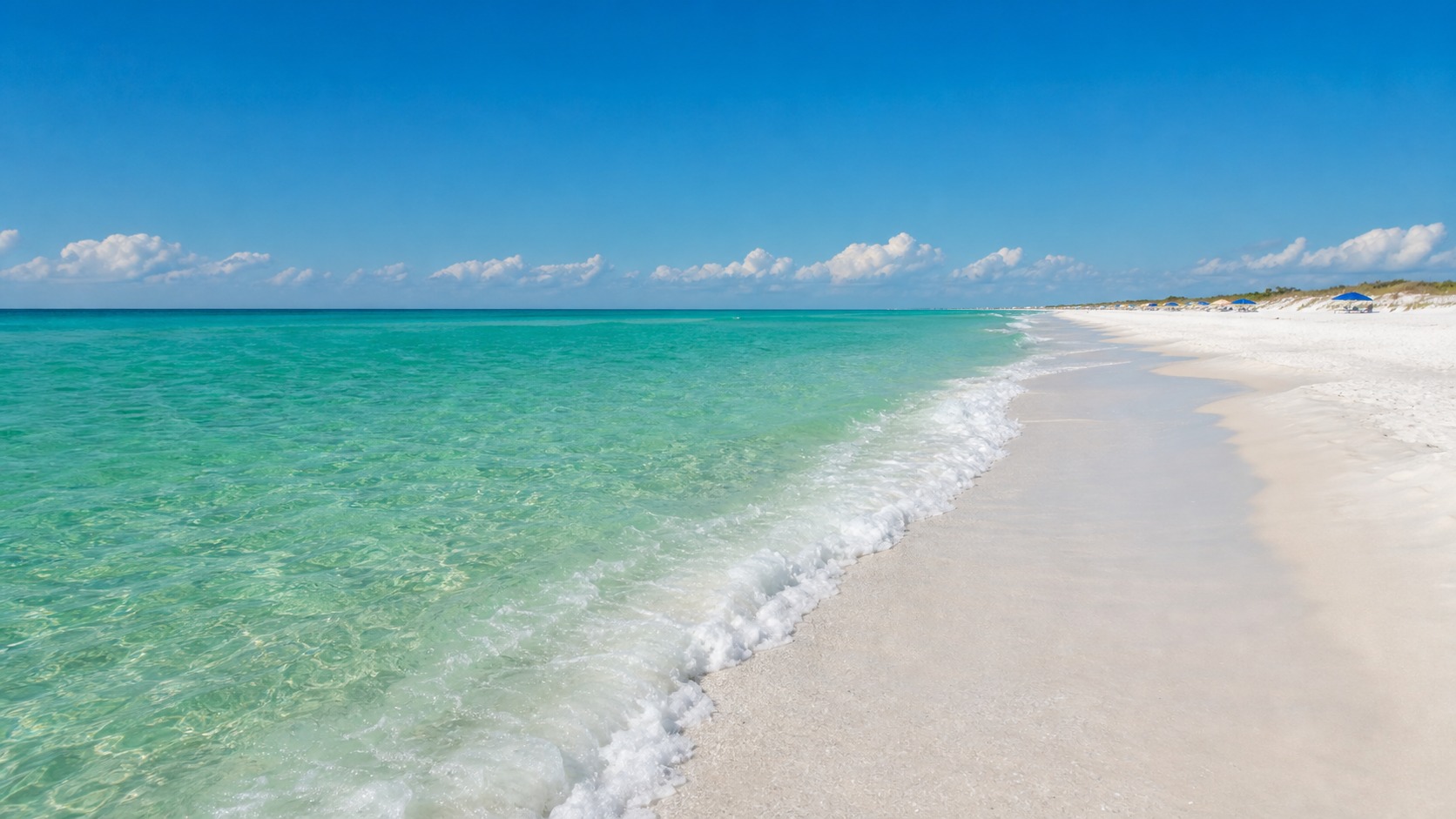 Crystal-clear emerald green Gulf of Mexico water meeting pristine sugar-white sand beach at Destin Florida on a bright sunny summer afternoon with gentle small waves