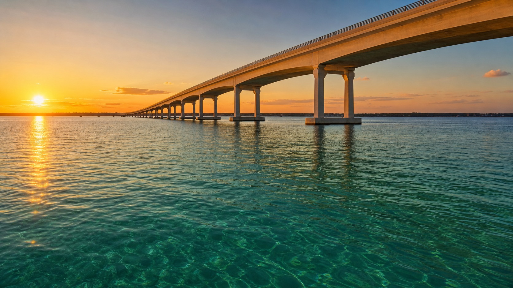 The Mid-Bay Bridge spanning the Choctawhatchee Bay in Destin Florida at golden hour sunset, emerald green water below