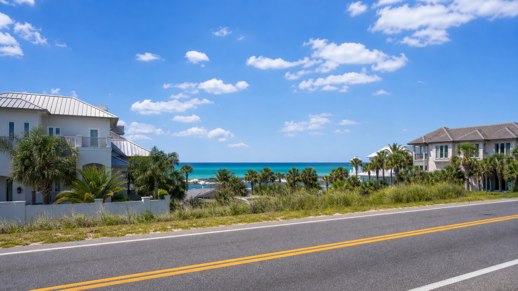 View of the emerald green Gulf of Mexico from US-98 driving east into Destin Florida on a sunny summer afternoon, turquoise water between coastal buildings and palm trees