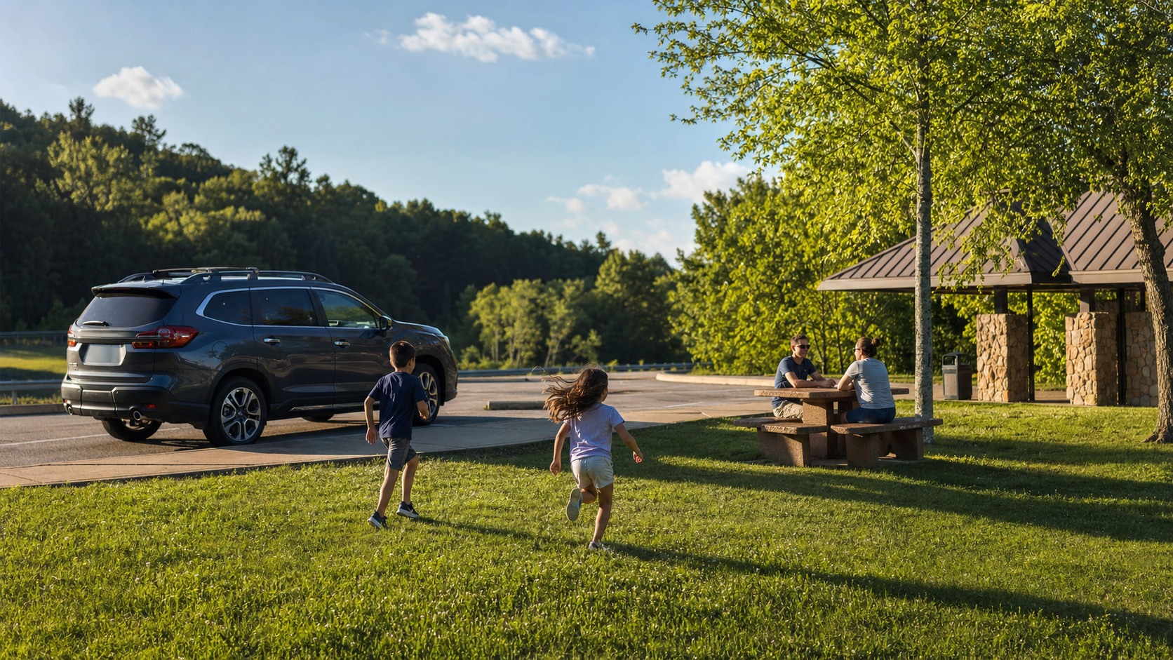 Family of four stretching legs at a Tennessee highway rest stop picnic area during a summer road trip, kids running on green grass, parents smiling near a parked SUV