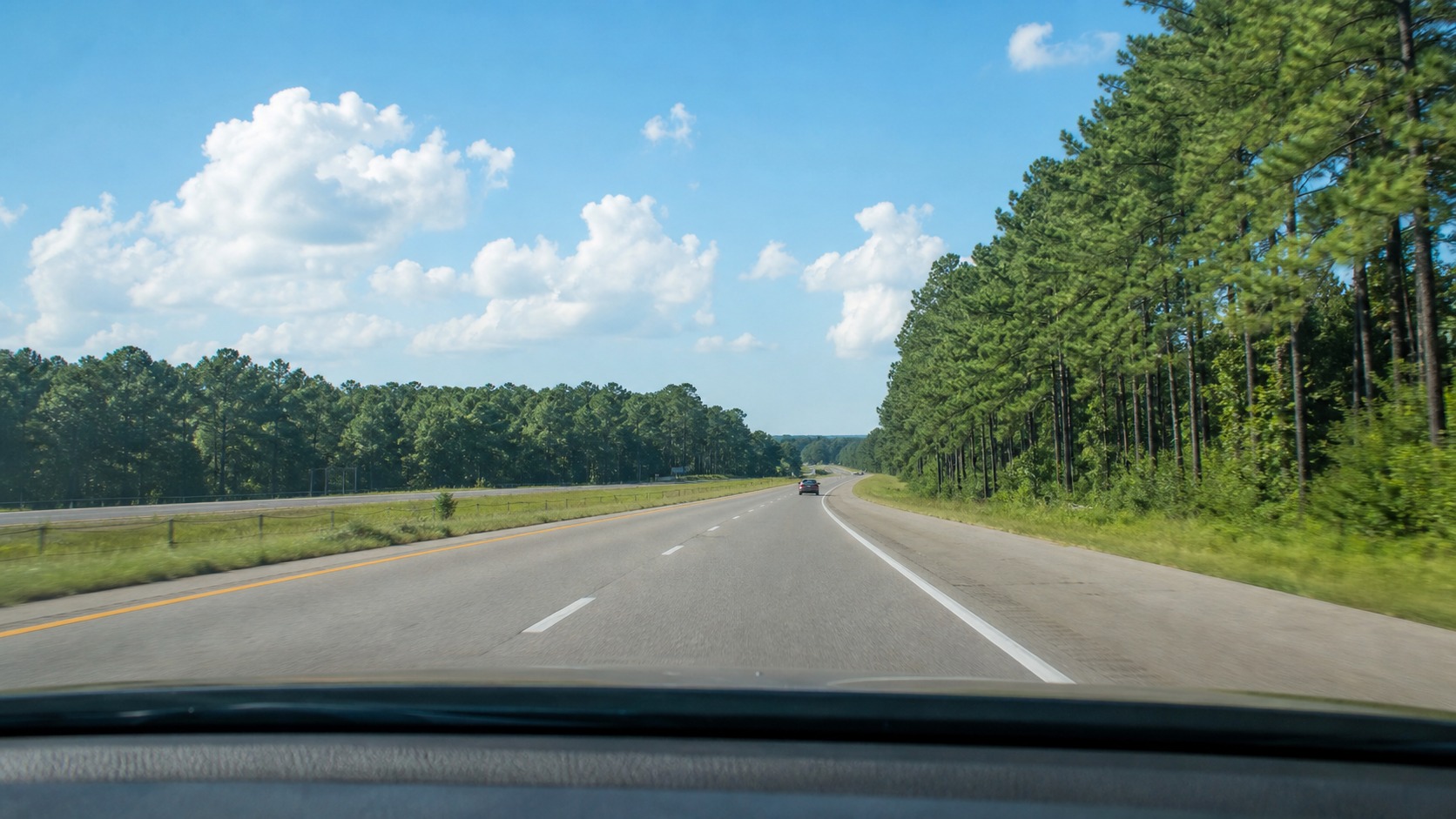 I-22 interstate highway heading southeast through Mississippi pine forest on a bright summer morning, open road with light traffic
