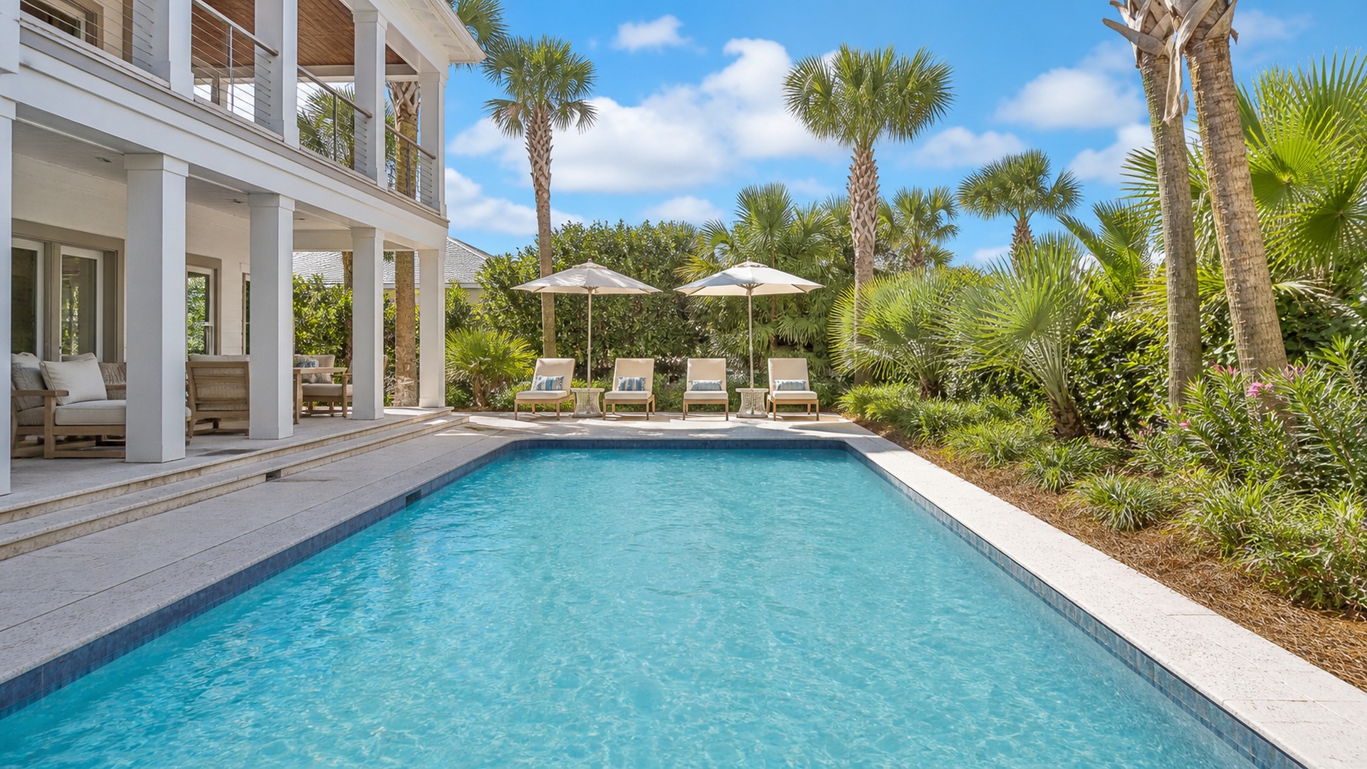 Private swimming pool of a vacation rental home in Miramar Beach Florida surrounded by lush tropical landscaping on a sunny summer afternoon