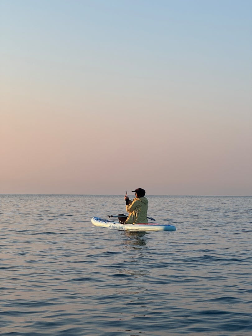 Solo paddleboarder in golden morning sunrise light on perfectly glassy calm water near Destin Florida