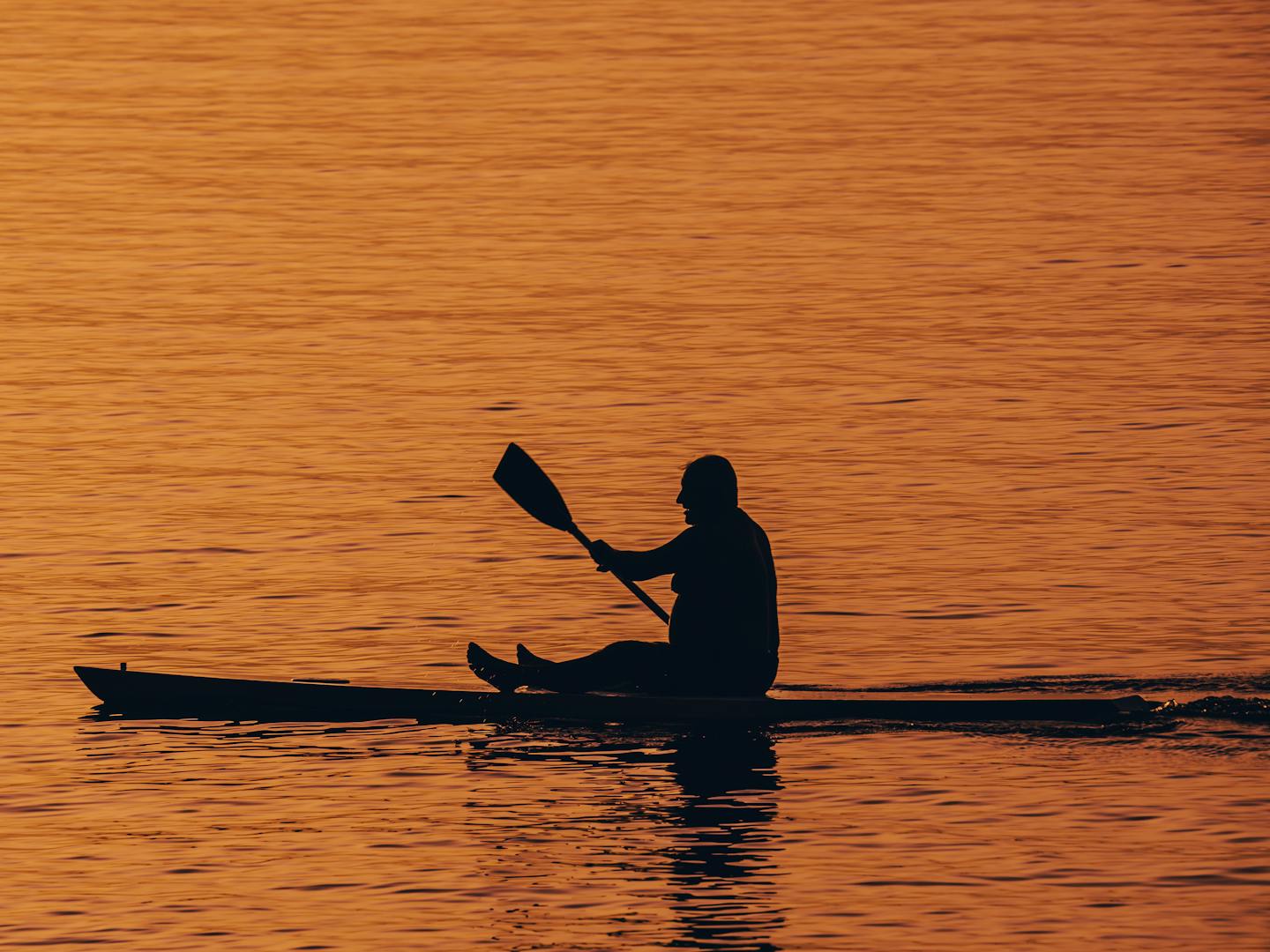 Evening kayak tour on calm Florida bay water with silhouettes of paddlers against a colorful sunset