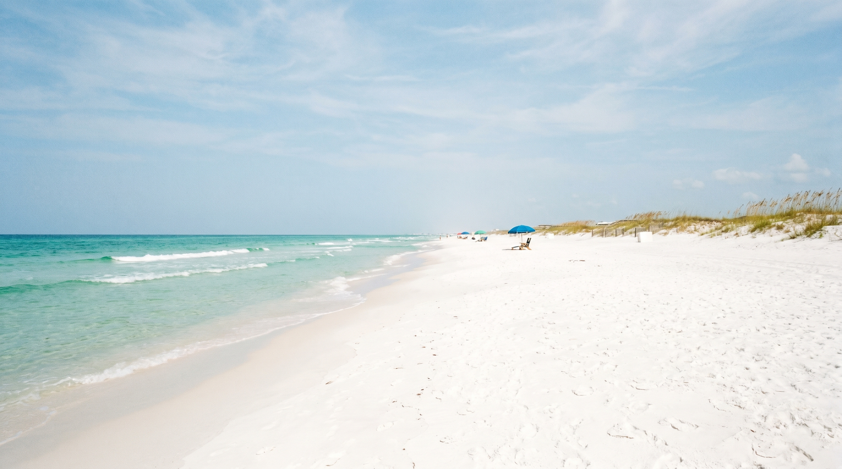 Uncrowded white sand beach in Destin Florida in May with emerald water and a few umbrellas