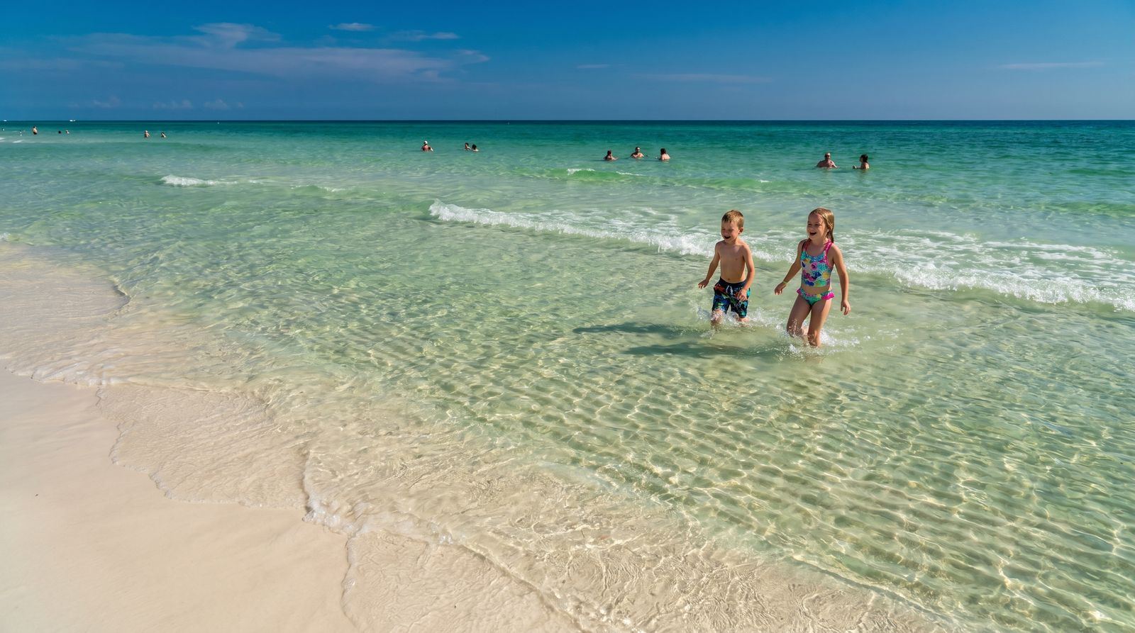 Crystal clear emerald green water and brilliant white sand at Destin's Gulf-front beach on a sunny summer afternoon