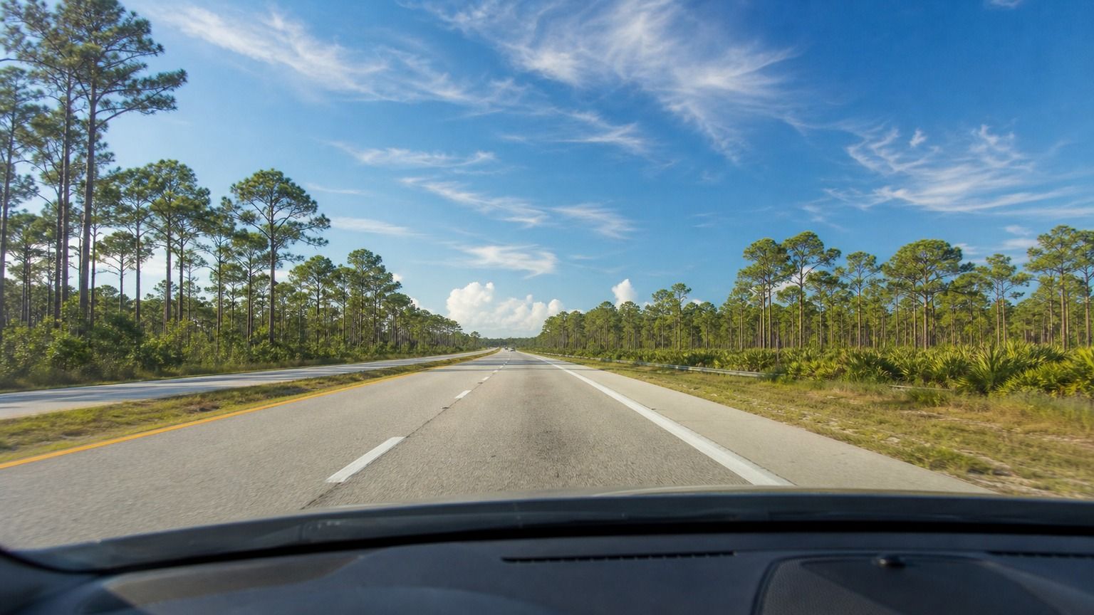 Open Florida highway through pine flatwoods on a sunny afternoon drive toward the Gulf Coast